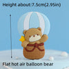 A flat hot air balloon bear cake topper made of fondant, featuring a brown bear with yellow accents.
