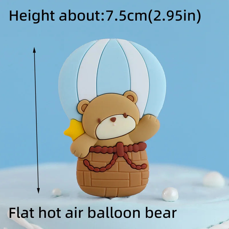 A flat hot air balloon bear cake topper made of fondant, featuring a brown bear with yellow accents.