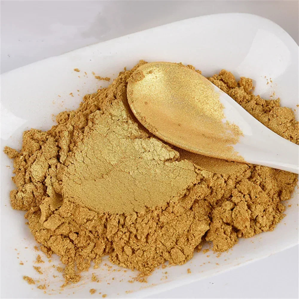 A spoonful of gold mica pearl powder is shown on a white dish for crafting materials.