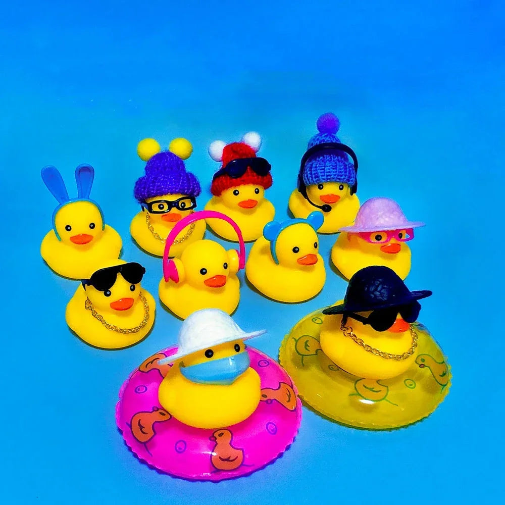 A collection of yellow rubber duck toys wearing various accessories like sunglasses, hats, and other items against a blue bac