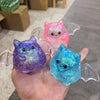 Three sparkly squeeze stress relief balls in purple, pink, and blue are held in a hand.
