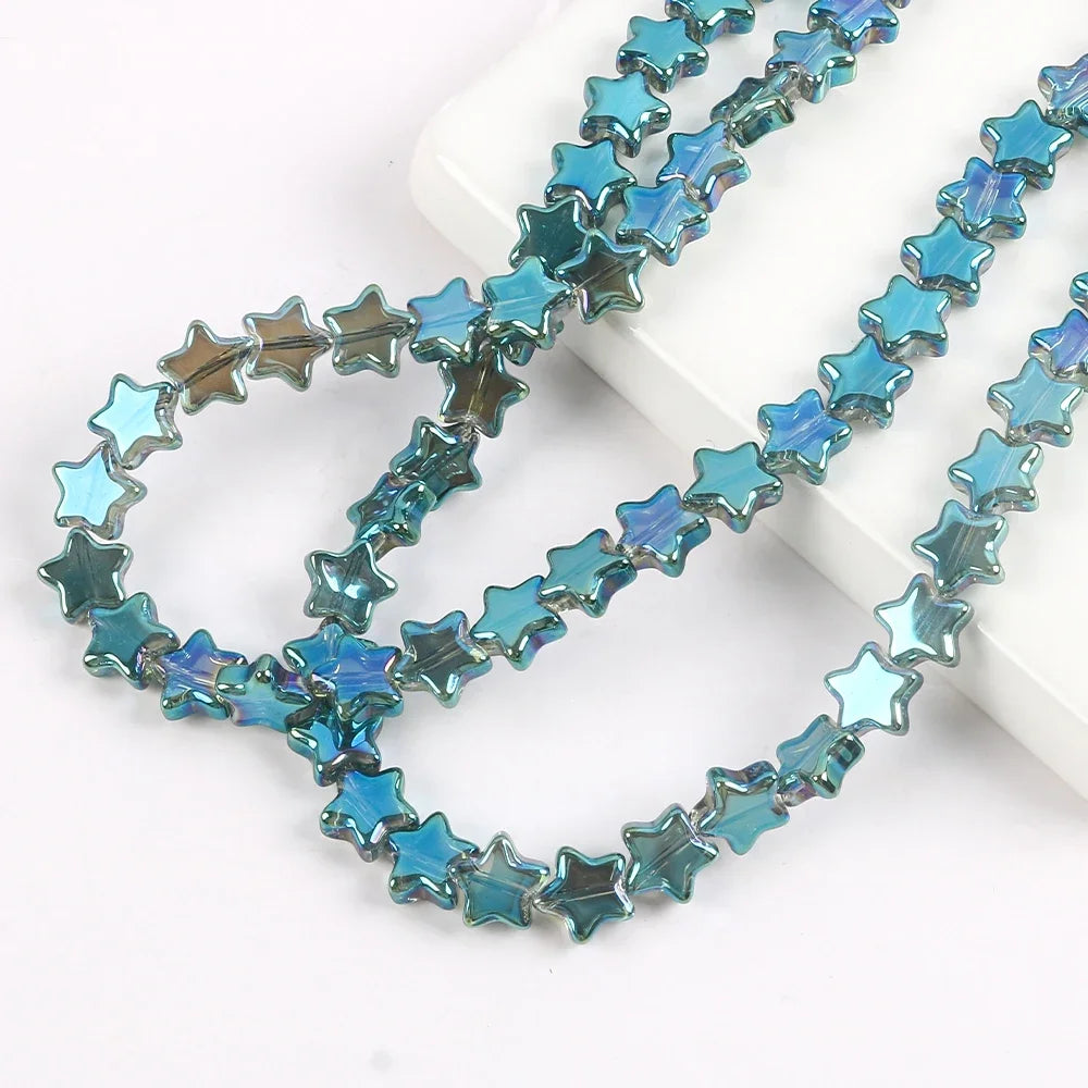 A strand of blue iridescent glass star spacer beads for jewelry making laid out on a white surface.
