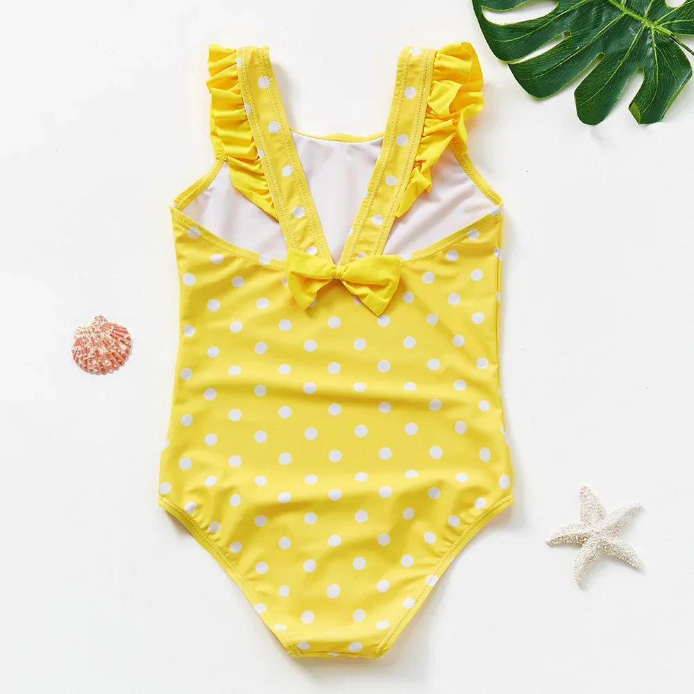 Yellow one-piece swimsuit for a child with white polka dots and ruffled trim