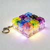 A collection of colorful LED light-up keycaps arranged in a plastic tray, attached to a metal keychain.