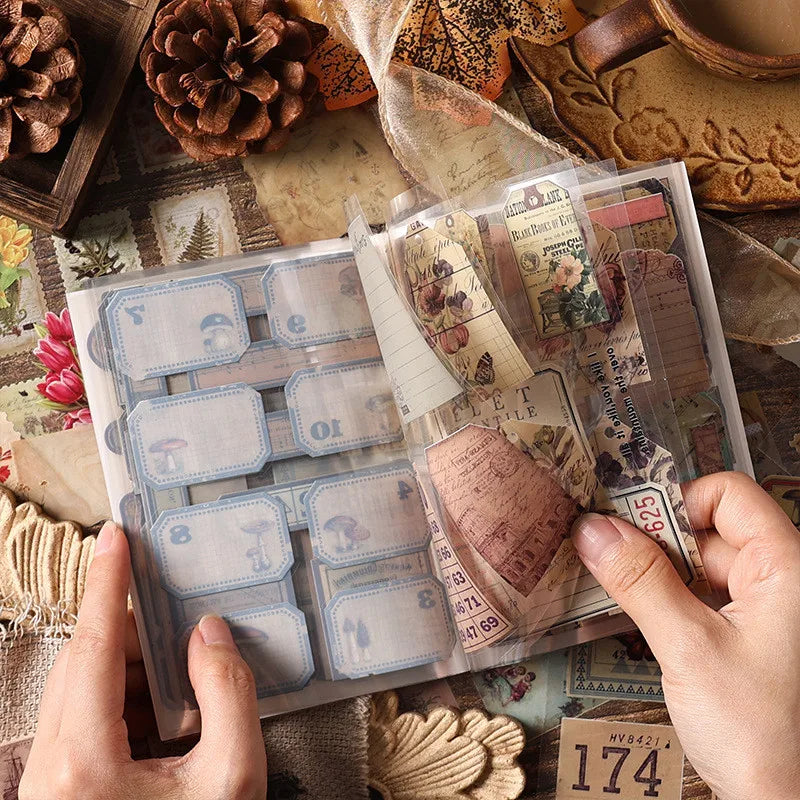 A hand holds a clear sheet of vintage PET sticker sheets for journaling and scrapbooking on a rustic wooden surface.