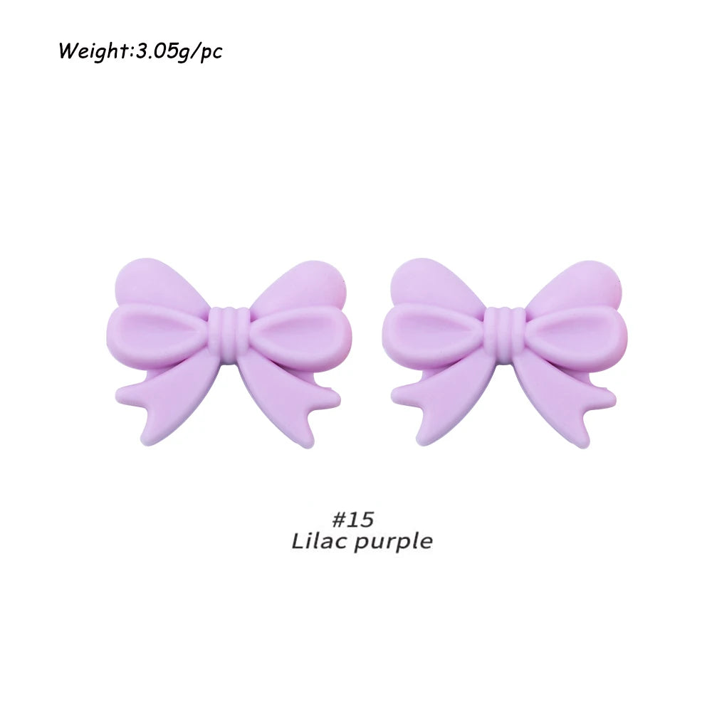 A pair of light purple silicone bow tie beads for jewelry making and craft projects.