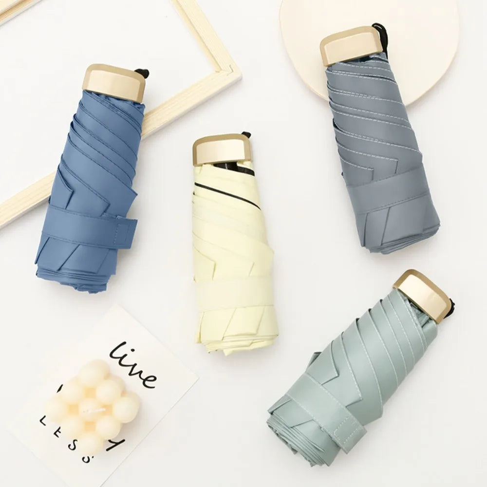 A stack of compact 5-fold sun and rain umbrellas in various shades of blue and beige.