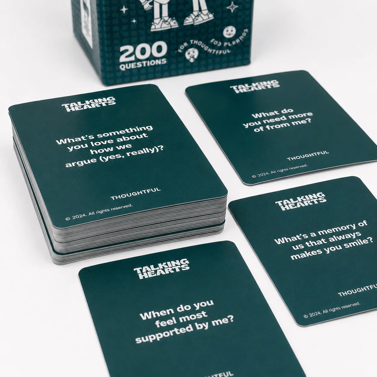 A stack of dark green talking hearts cards with questions for couples conversation displayed on a white background.