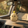Hand-crocheted yellow frog ornament hanging from a rearview mirror inside a car