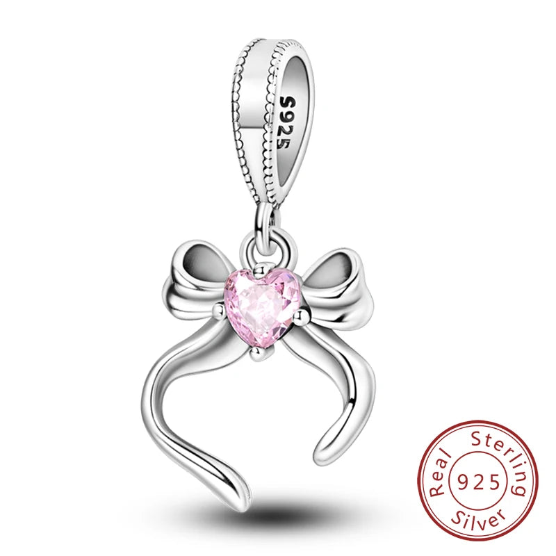 A sterling silver heart charm bead with a pink gemstone and a bow design.