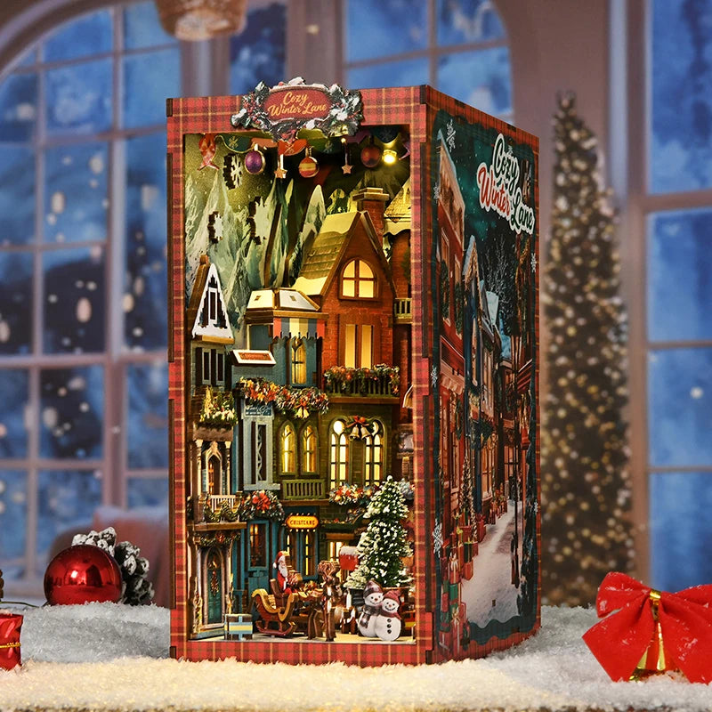 A wooden book nook kit featuring a detailed Christmas street corner miniature model with lights and seasonal decorations.