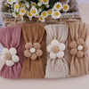 A collection of floral elastic baby headbands in various neutral and pink tones displayed in a woven basket.
