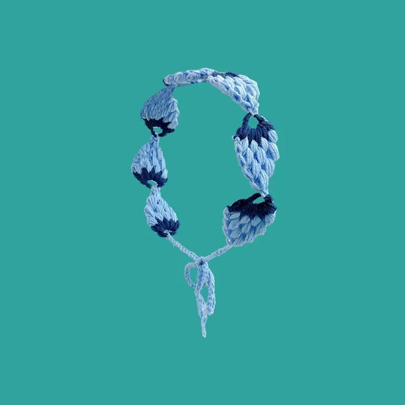 A light blue crochet headband with a wide elastic band against a teal background.