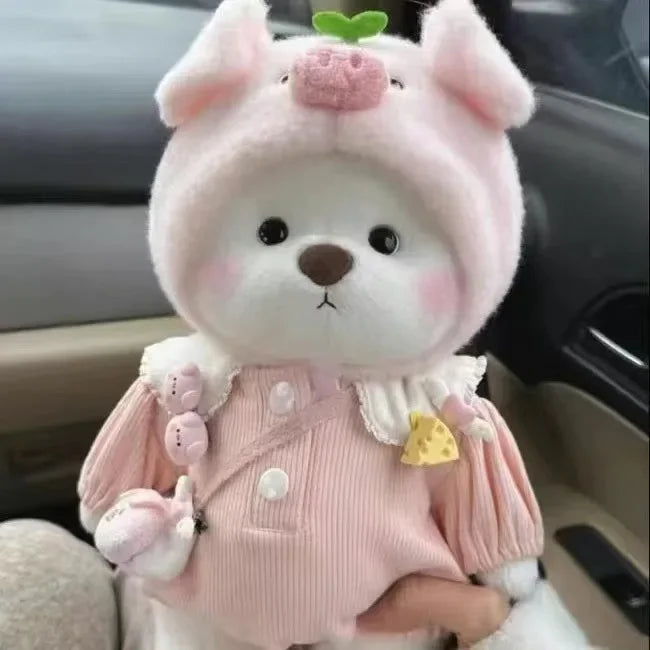 A pink and white plush teddy bear with a frilly dress and a green accent.