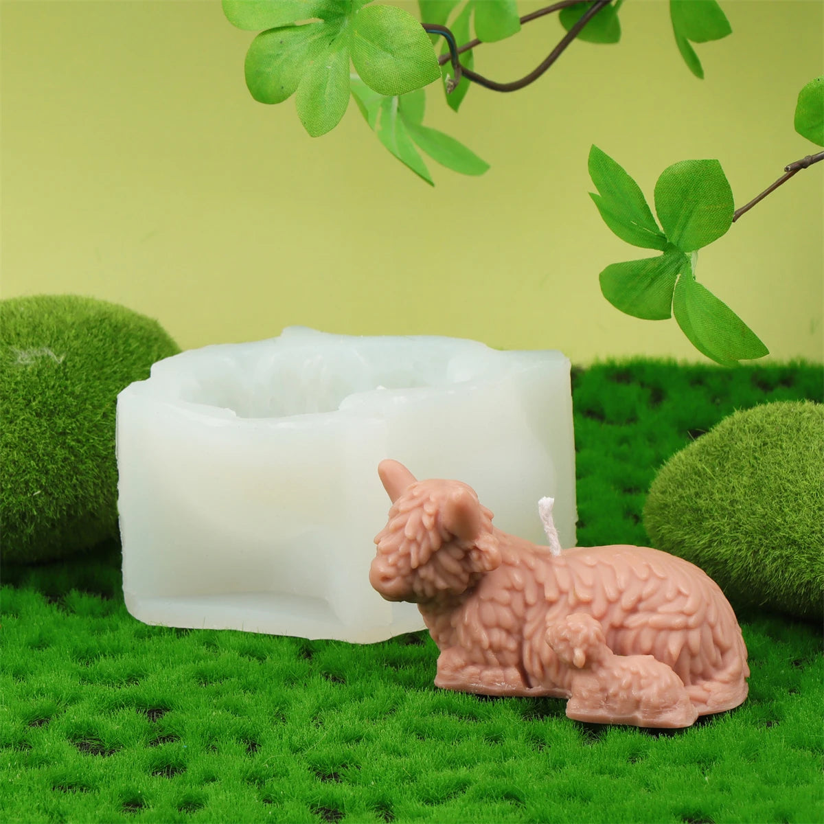 A silicone candle mold set featuring a pink highland cow design resting on green moss.