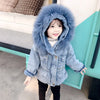 A young girl wearing a light blue denim jacket with a fluffy faux fur collar and dark pants.