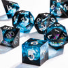 A collection of black polyhedral dice with a blue galaxy finish are scattered on a white surface.