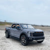 A dark gray 1:20 scale Ford Raptor F150 diecast model truck parked on a concrete surface.