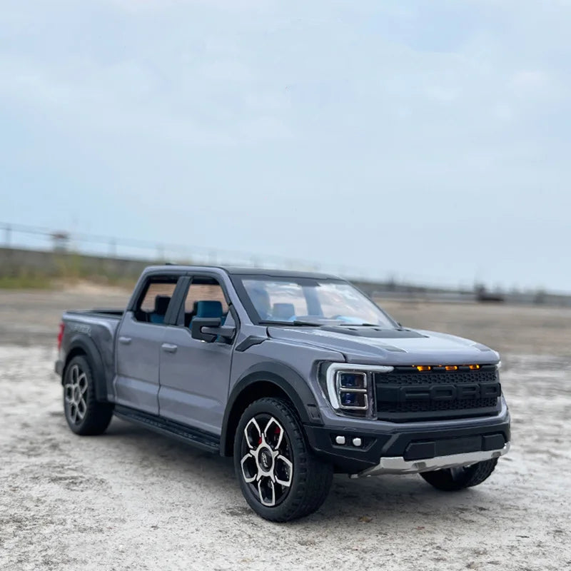 A dark gray 1:20 scale Ford Raptor F150 diecast model truck parked on a concrete surface.
