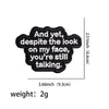 Black embroidered patch with the text And yet despite the look on my face you're still talking.