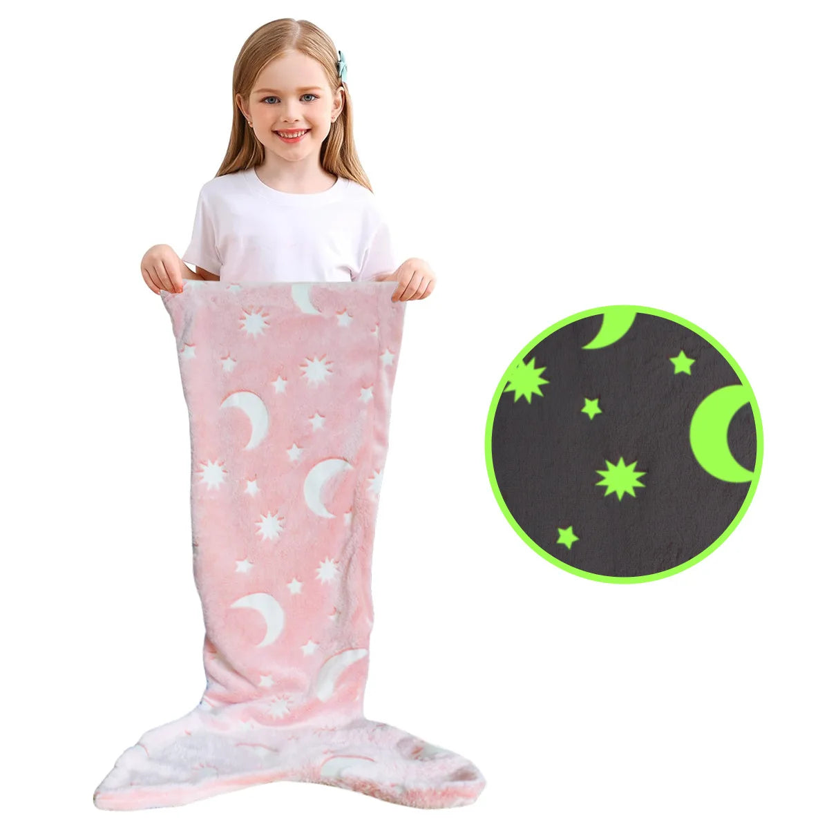A young girl is holding a pink glow-in-the-dark mermaid tail blanket with a black background featuring green stars and a cres