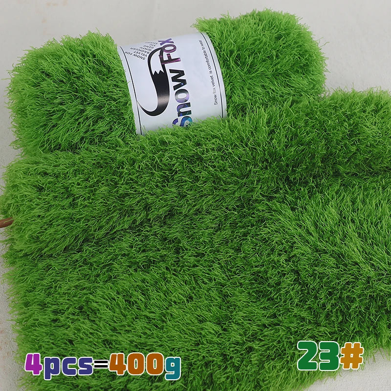 A green faux fur yarn is displayed with a roll of Snow Fox yarn in the foreground.