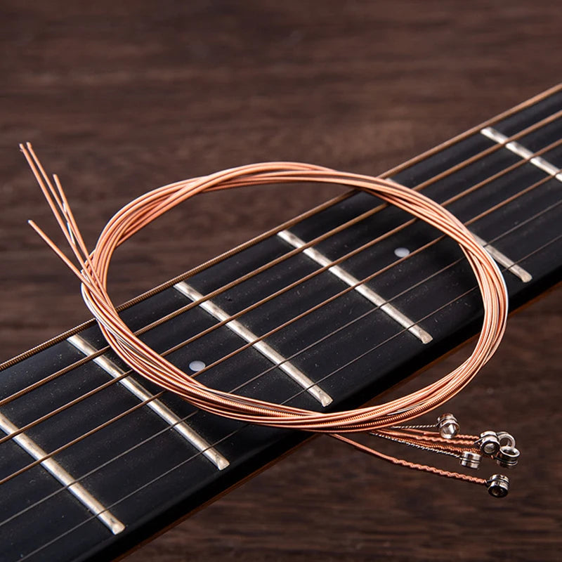 A close-up of copper guitar strings coiled around a fretboard with a string changer tool.