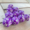 A pile of ten purple pearl acrylic D20 dice resting on a wooden surface.