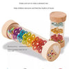 A wooden rain sound shaker toy with colorful plastic raindrops is shown next to a jar, designed to help babies build a sense 