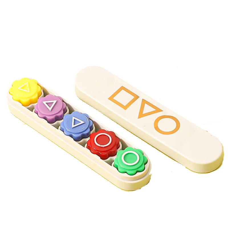 A set of five colored gonggi stones used for a traditional Korean game, arranged on a light wooden board.