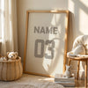 A framed canvas wall art featuring the name and number 03 in gray on a beige background