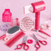 A pink hair dryer and various red plastic hair tools including combs, brushes, and scissors for a kids' pretend play beauty s