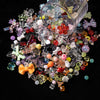 A collection of mixed clear and colored acrylic bow and flower beads scattered on a dark surface.