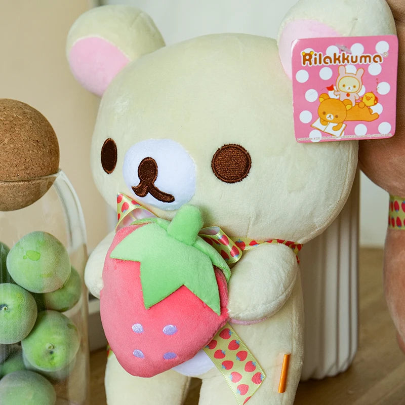 A fluffy white Rilakkuma bear plush toy with a pink strawberry accessory and packaging.