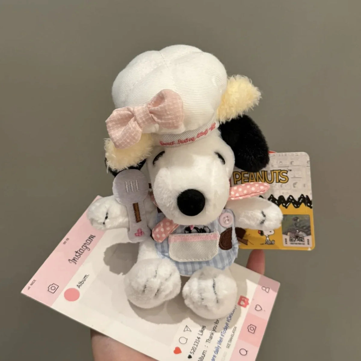 A white Snoopy plush keychain charm is shown against a light background.