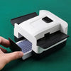 A hand is holding a portable automatic card shuffler with a white and black casing, showing the mechanism for shuffling cards