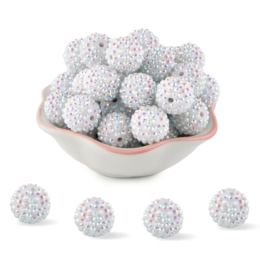 A pile of small, round, silver and iridescent rhinestone resin beads for jewelry making.
