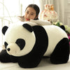 A white and black panda plush pillow resting on a white surface.