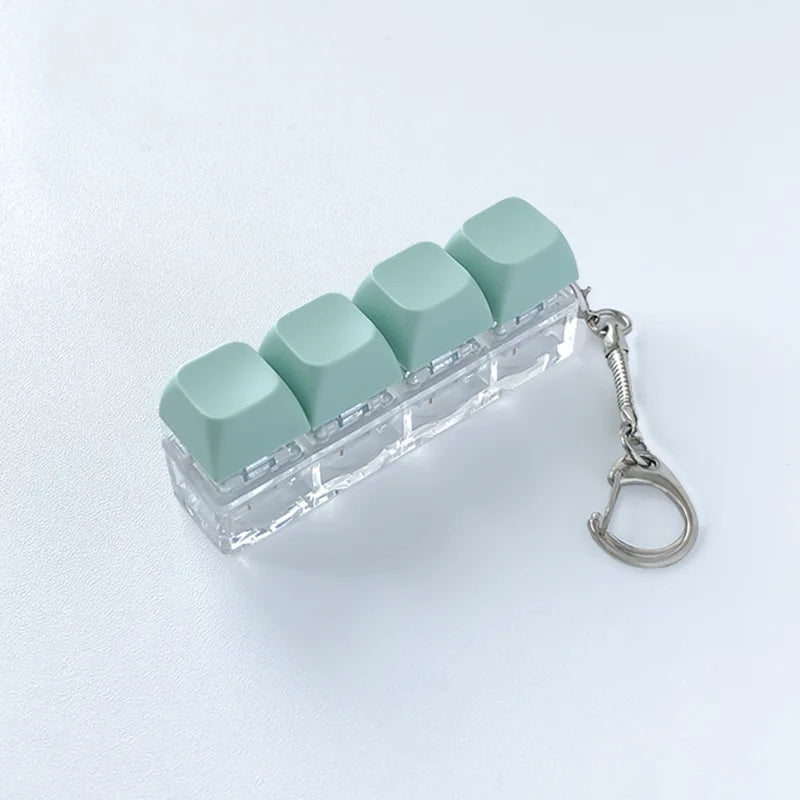 Clear acrylic fidget keychain with four light green clicky key buttons attached to a silver keyring