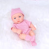 A realistic soft vinyl reborn baby doll wearing a pink striped outfit and matching hat, lying on white fluffy material.