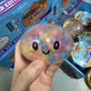 Une main tient un jouet anti-stress en forme de dumpling perlé et multicolore dans sa boîte.