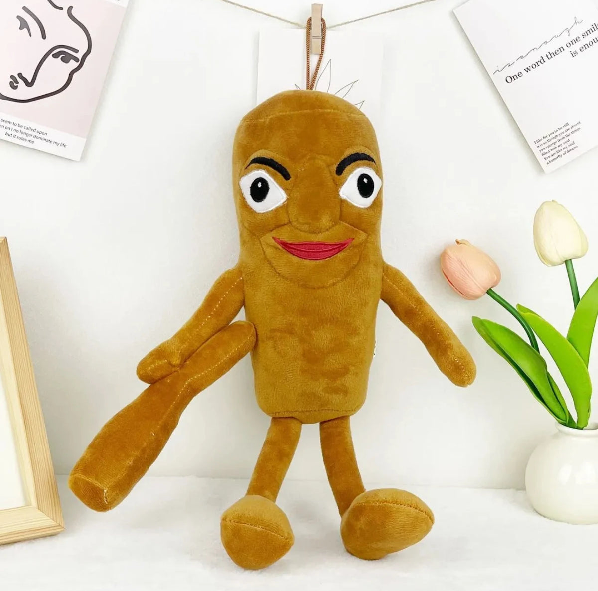 A brown, plush shark toy with large eyes and a smiling face is displayed against a white background.