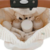 A quilted white diaper bag with embroidery is shown open, revealing soft fabric lining and various small items.