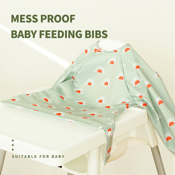 A light green mesh baby feeding bib with a white floral pattern is displayed on a white table.