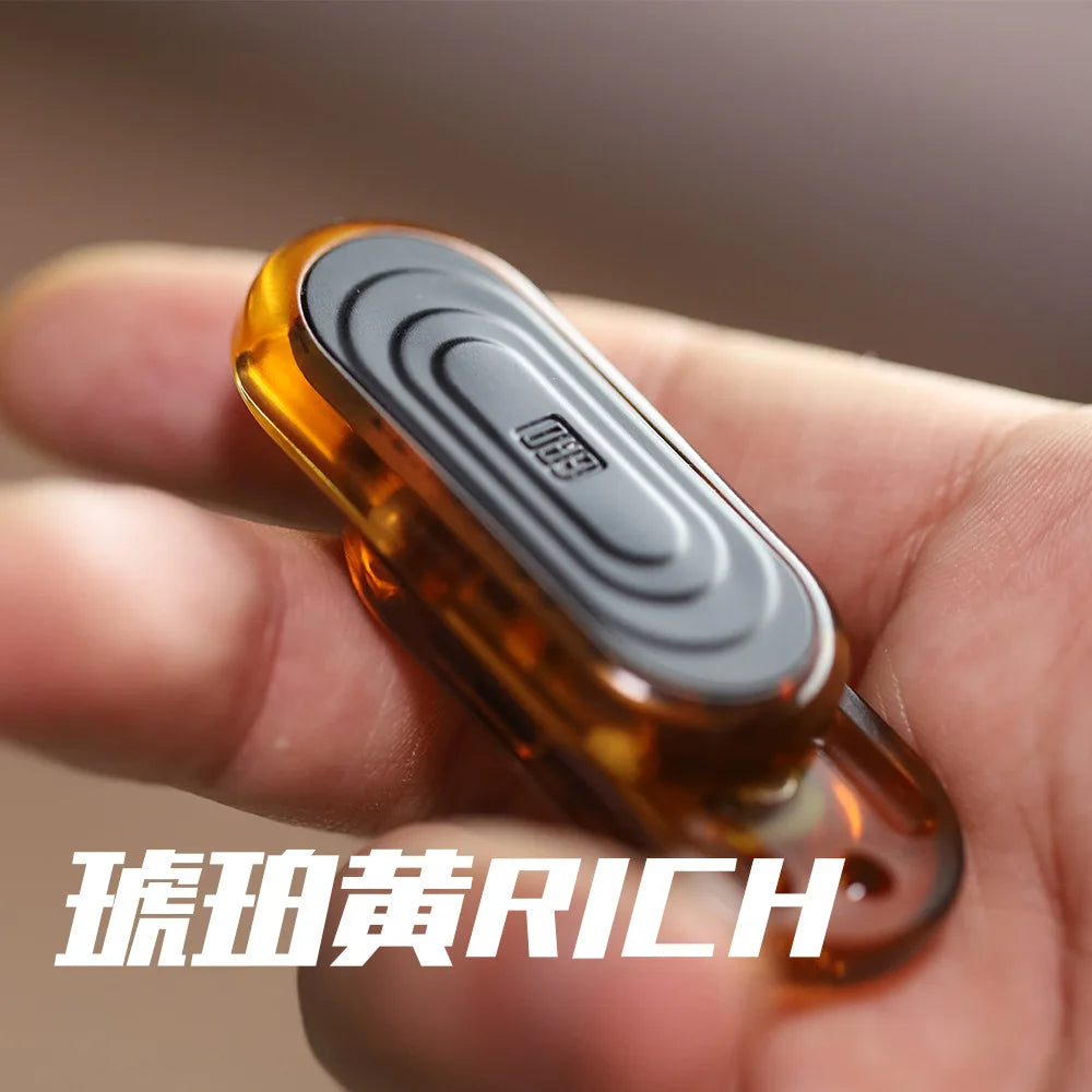 A hand holds an amber-colored EDC push slider fidget toy with a silver ring.