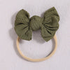 A soft olive green fabric bow headband with a light beige elastic band.