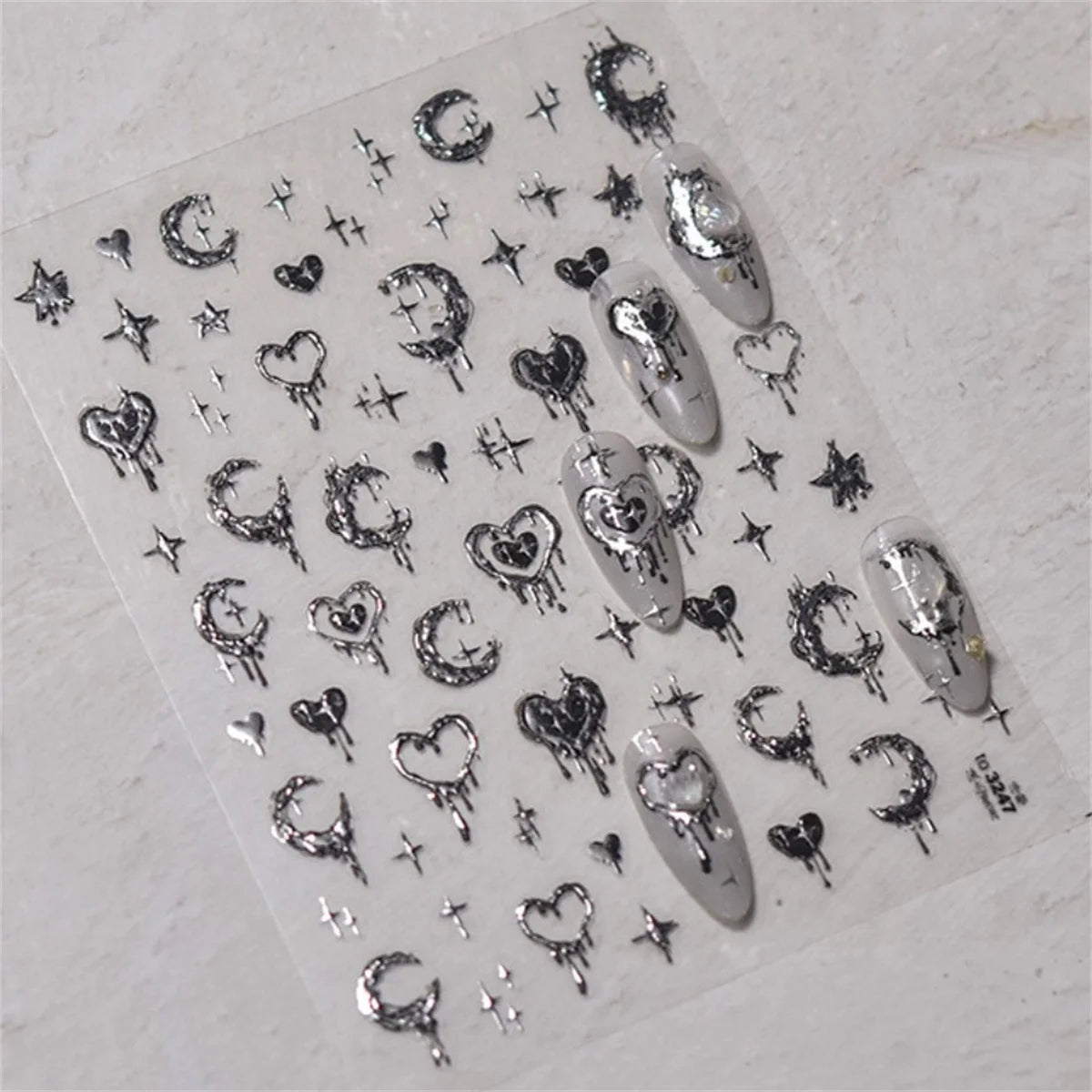 A collection of silver and black gothic nail art stickers featuring skulls, bats, stars, and hearts on a clear sheet.