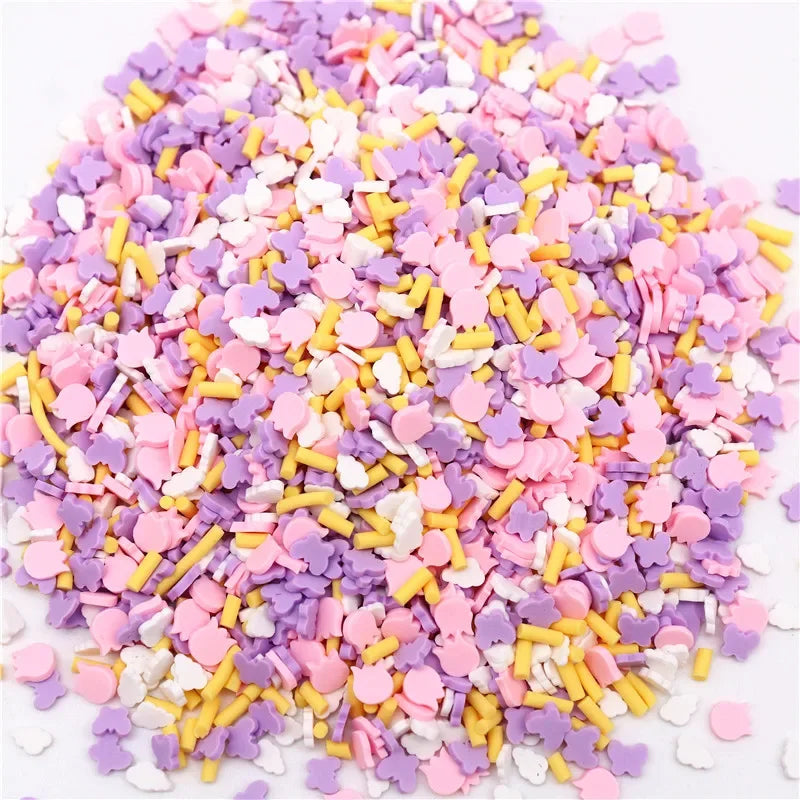 A pile of colorful polymer clay flower charms in various shades of pink, purple, and yellow.