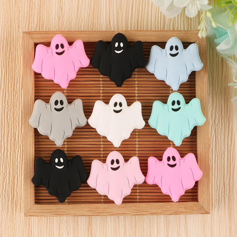 A set of five silicone ghost beads in various pastel colors are arranged in a wooden tray.