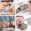 Hands are shown using precision tools to repair and examine a watch movement.